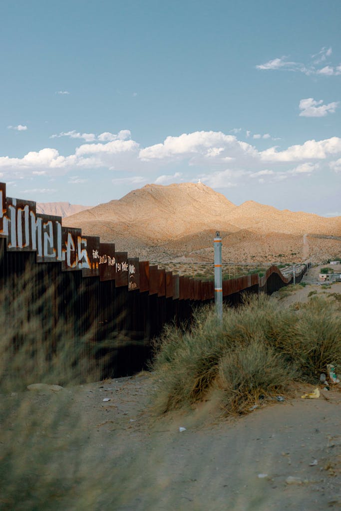 Desert scene with border wall in Ciudad Juárez under a bright sky.